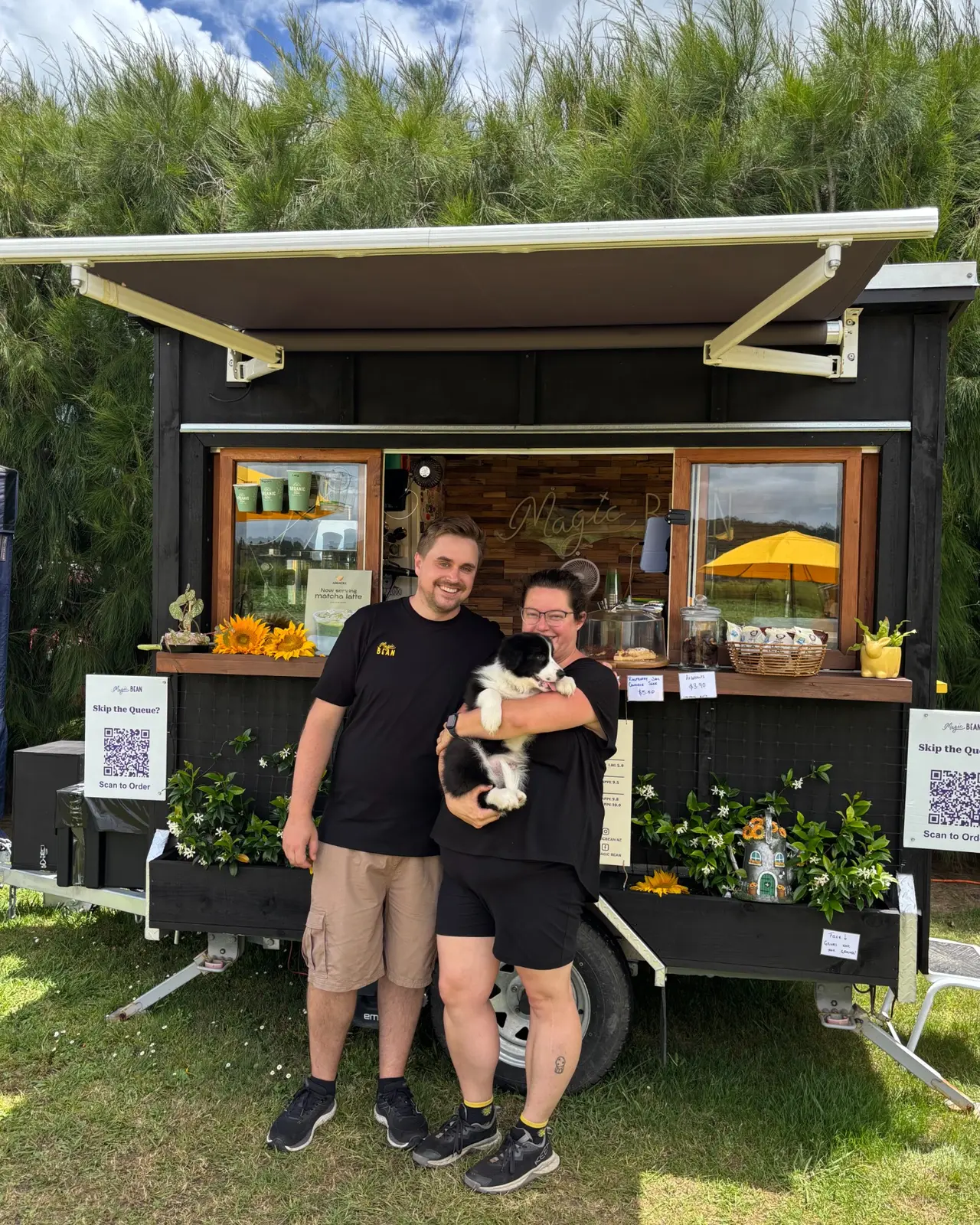 Sam and Jade with a dog in front of the Magic Bean cart with its awning open